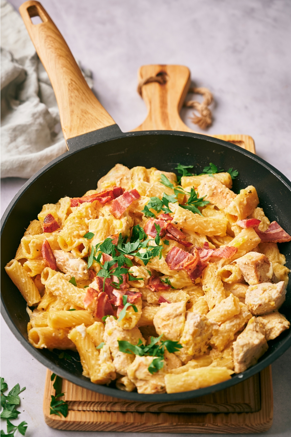 A large skillet with crack chicken pasta garnished with parsley.