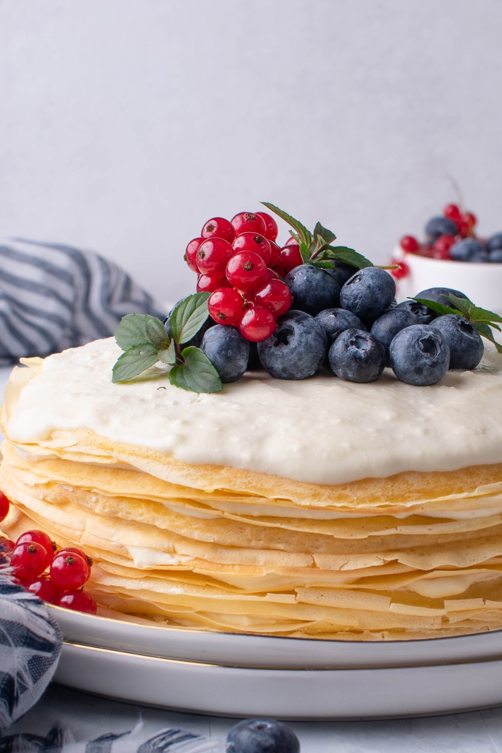 A close up of an entire crepe cake topped with blueberries and grapes.