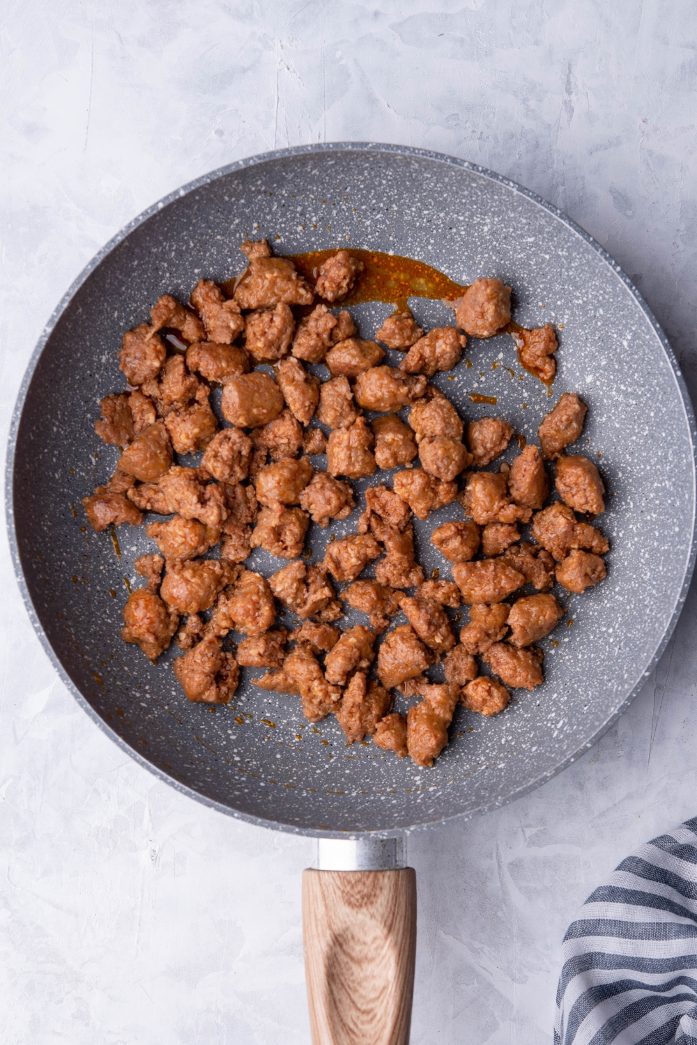 A skillet with browned sausage in it.