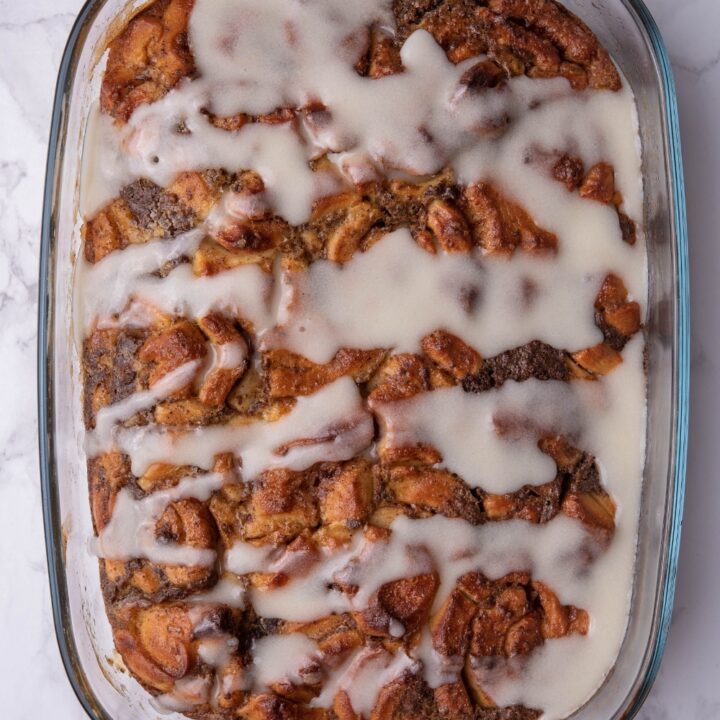 Icing on top of cinnamon roll casserole in a baking dish.