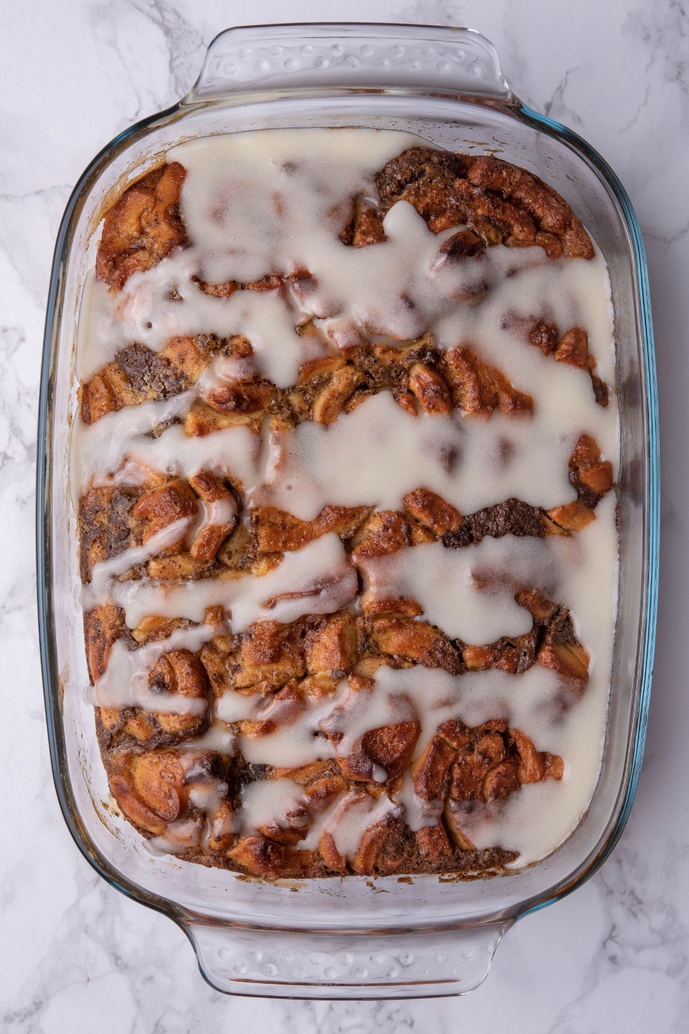 Icing on top of cinnamon roll casserole in a baking dish.
