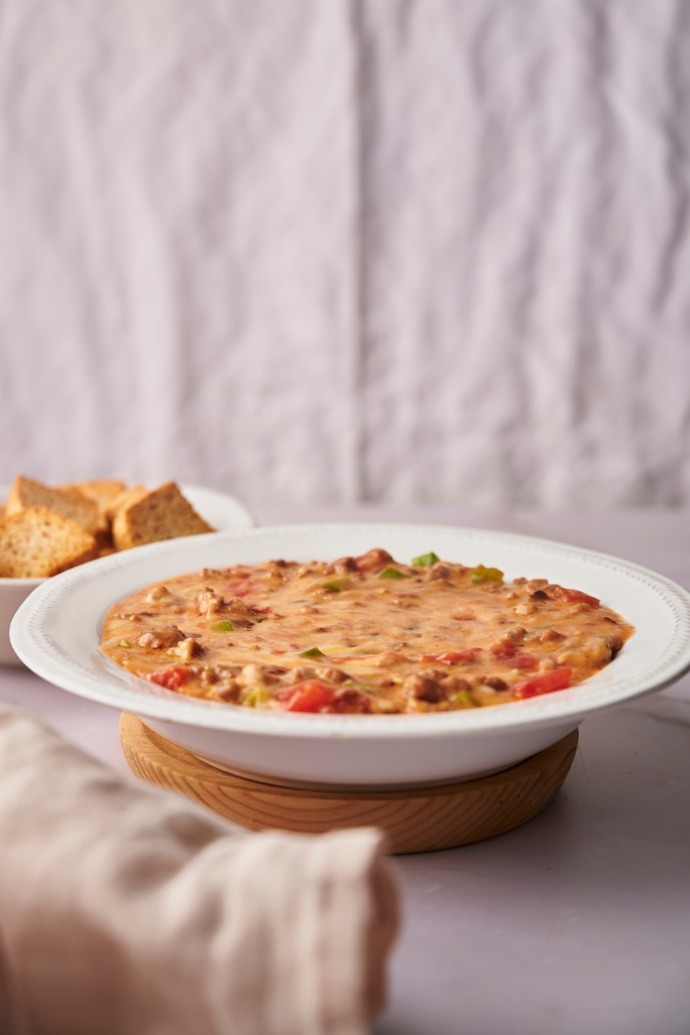 Rotel dip in a white bowl on a wooden serving board.