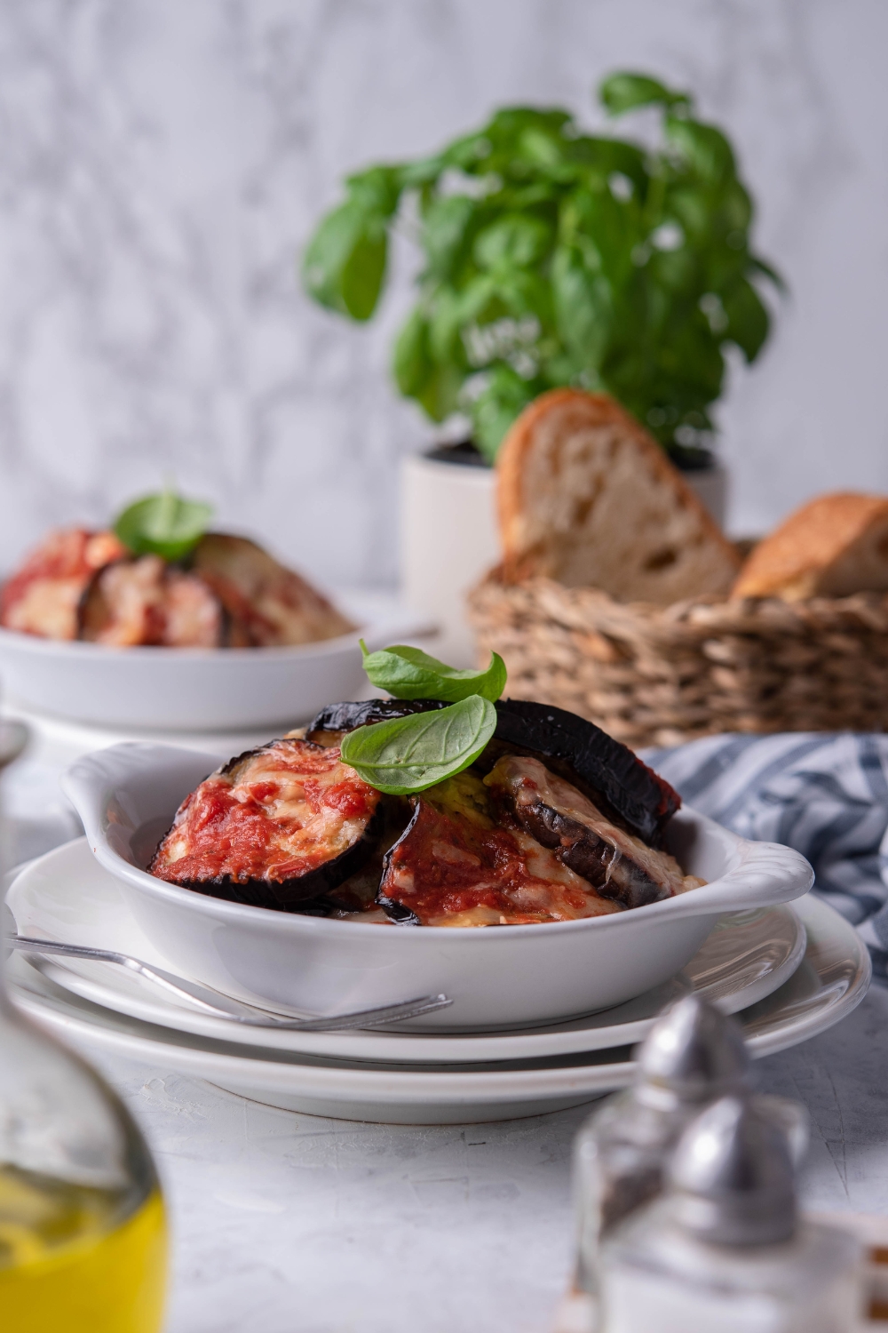 Eggplant parmesan slices in a white bowl on top of a plate.