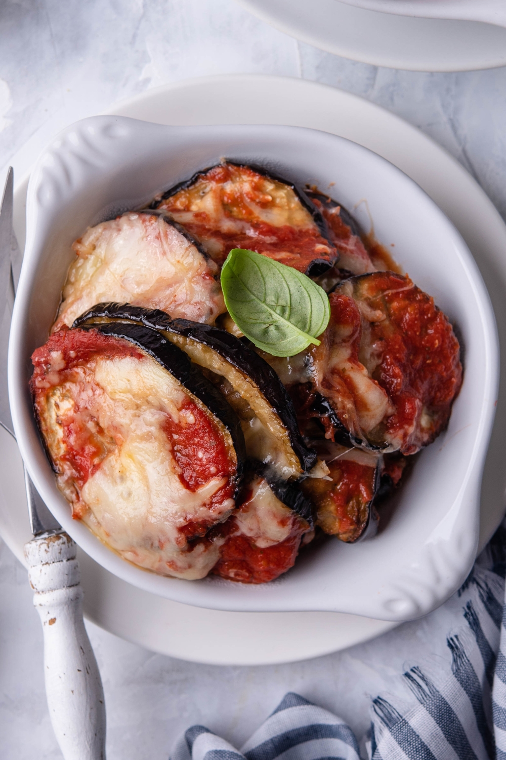 Eggplant parmesan slices in a white bowl.