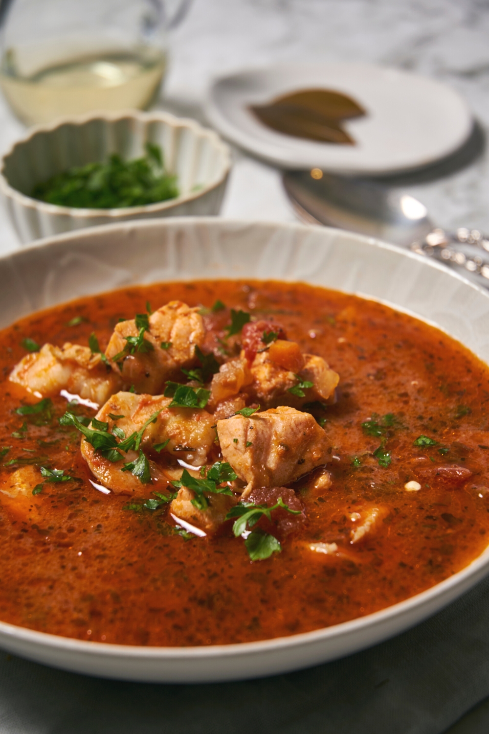 A bowl of seafood soup with shrimp and salmon on top of of the broth.