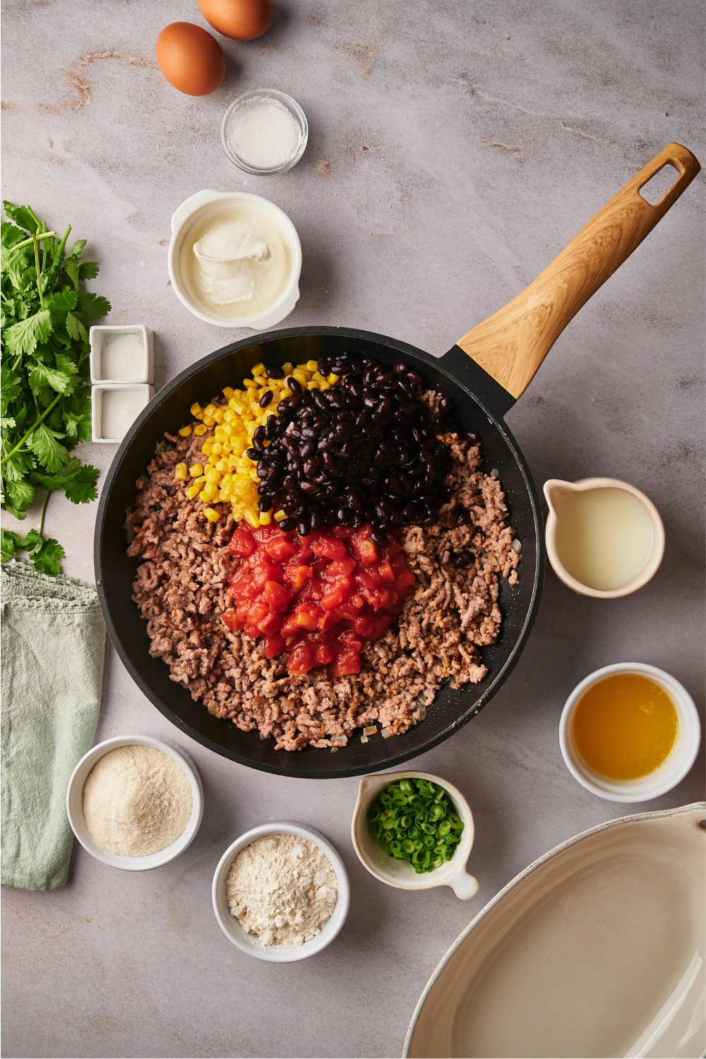 browned ground beef, black beans, crushed tomatoes, and corn in a skillet.