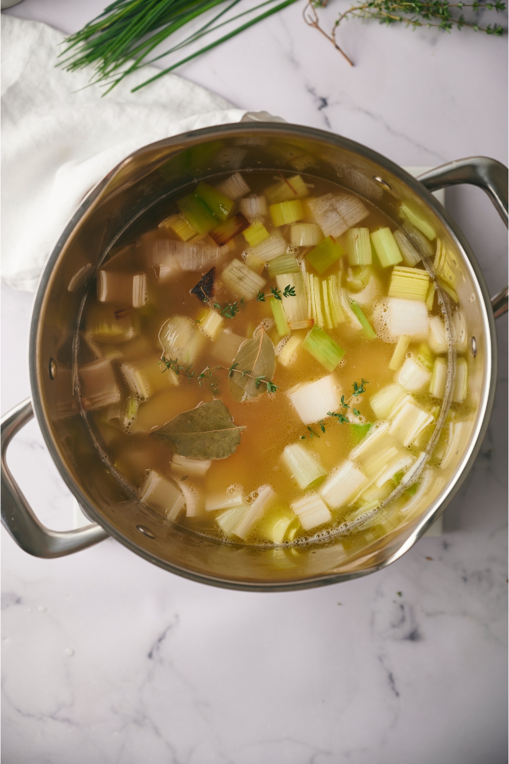 Chopped leeks and potatoes in broth in a pot.