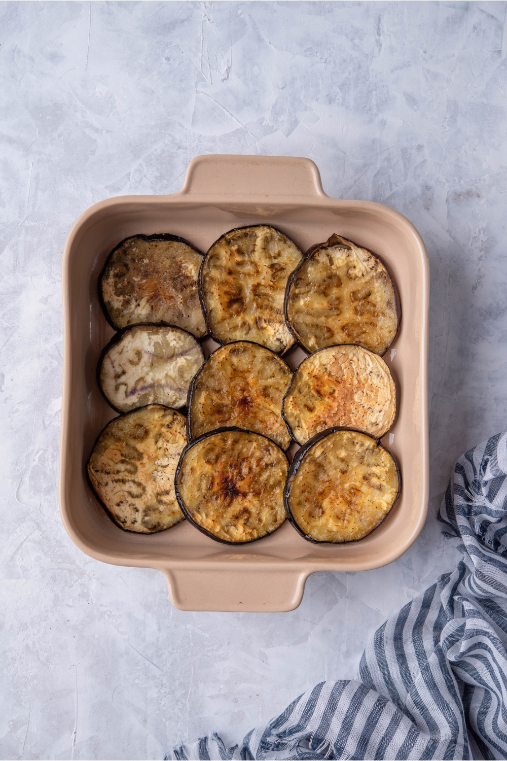 Three rows of three baked eggplant slices in a casserole dish.