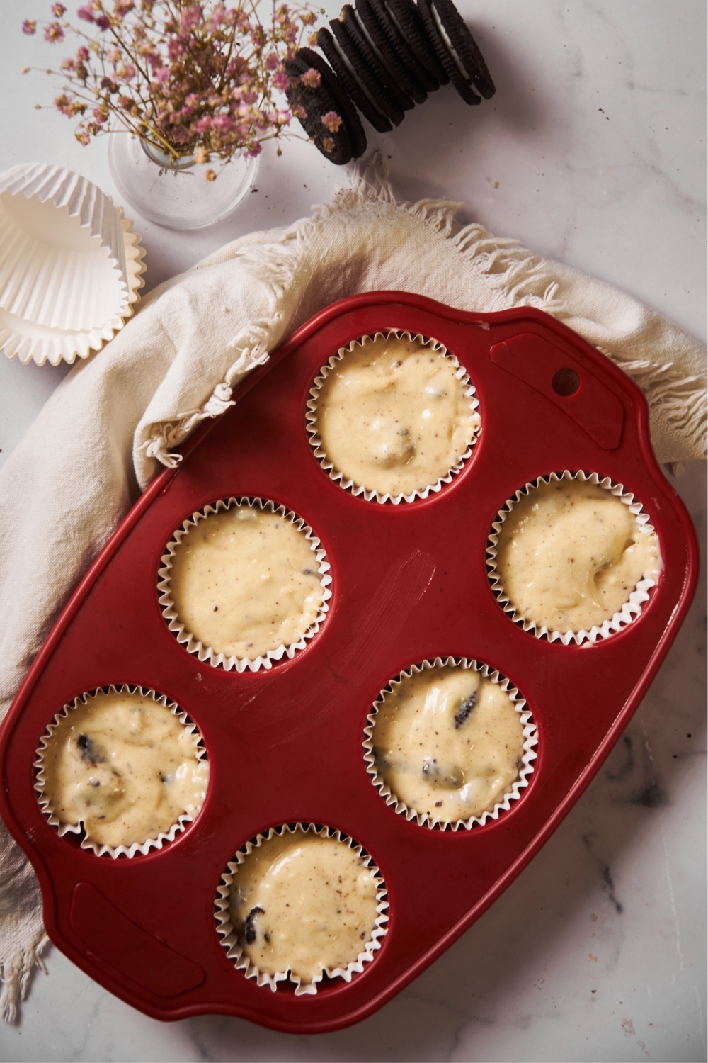 Six unbaked cupcakes in a red cupcake tray.