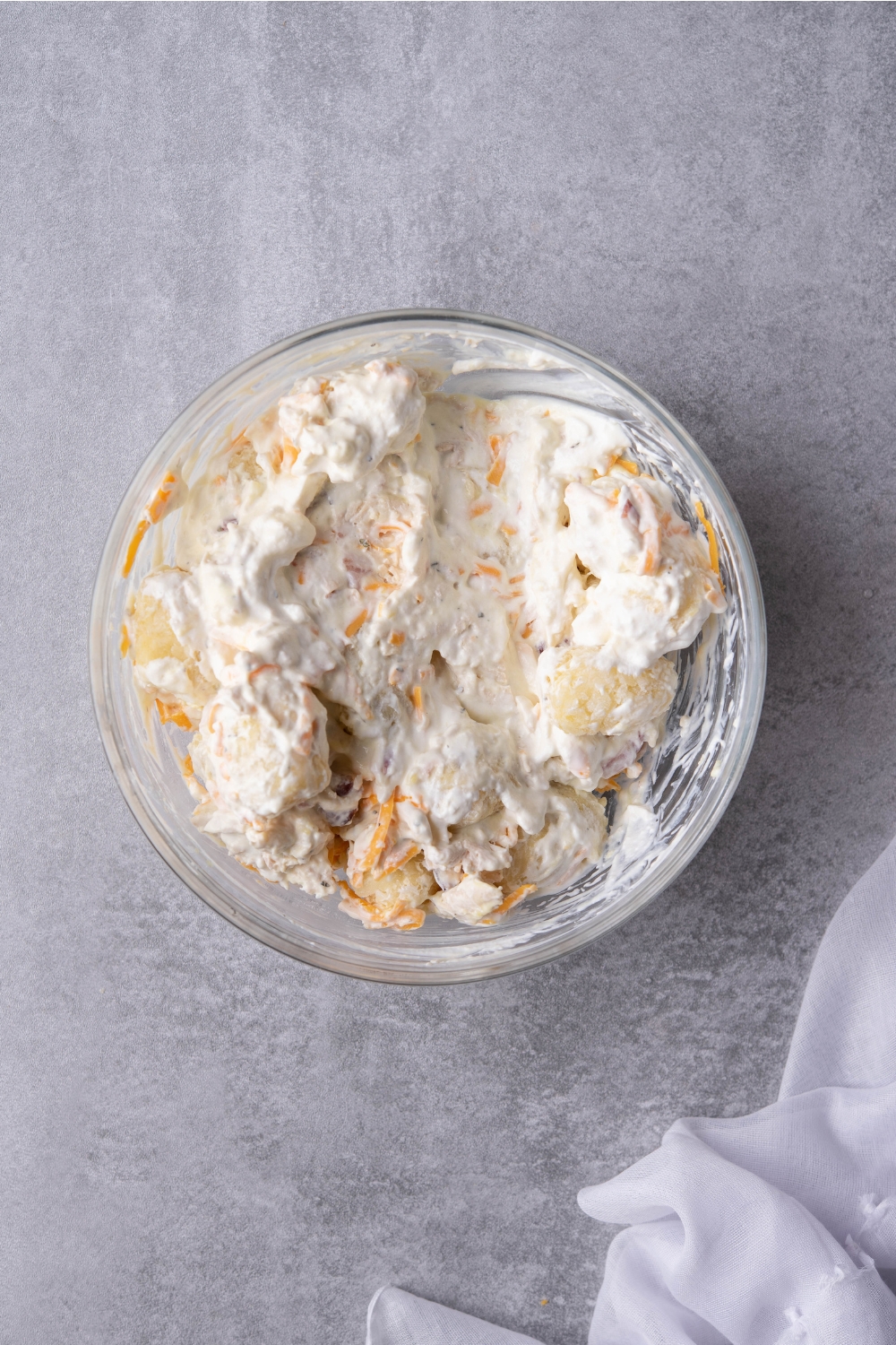 Sour cream and cheese mixture in a glass bowl on a gray counter.