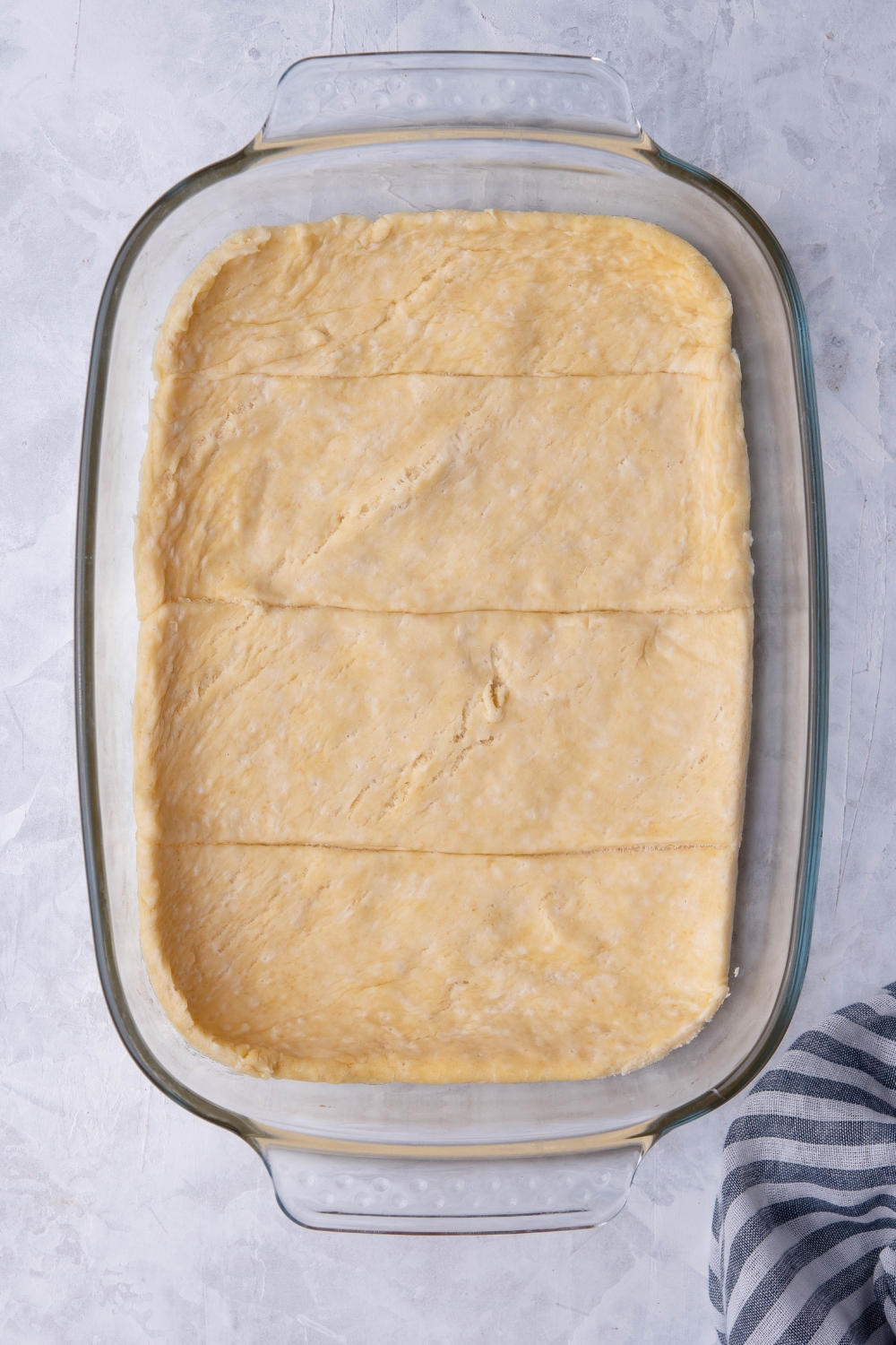 A casserole dish lined with unraveled crescent roll dough.