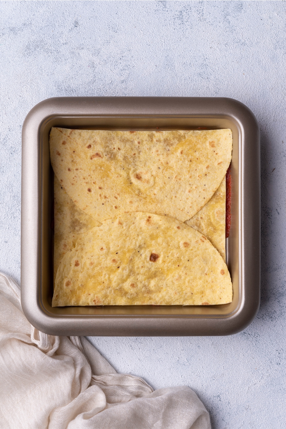 Halved tortilla shells in a square baking dish.