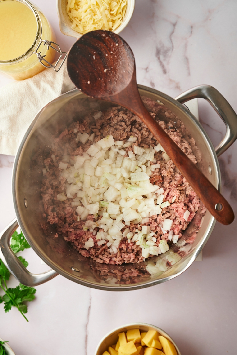 Diced onion on top of ground beef cooking in a large pot.