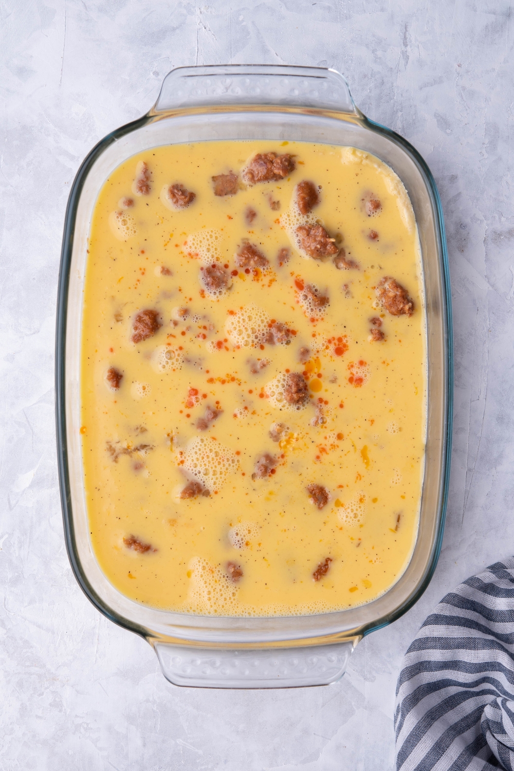Egg mixture on top of sausage pieces in a casserole dish.