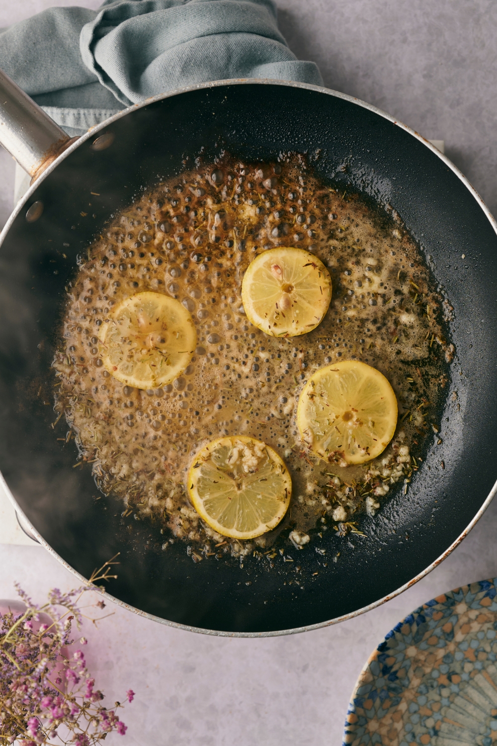 A frying pan with lemon butter sauce cooking in it.
