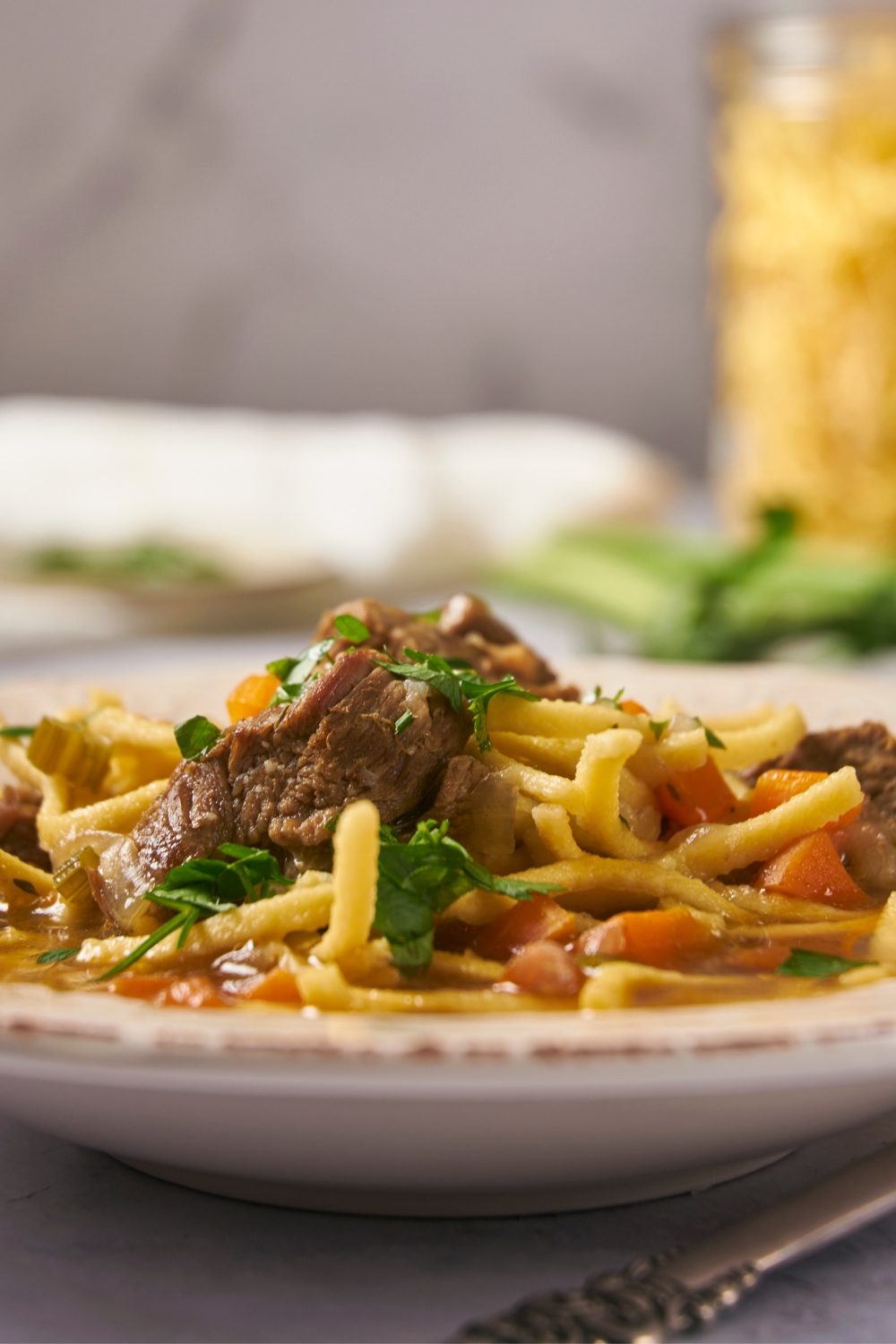 Beef cubes and noodles in part of a bowl.