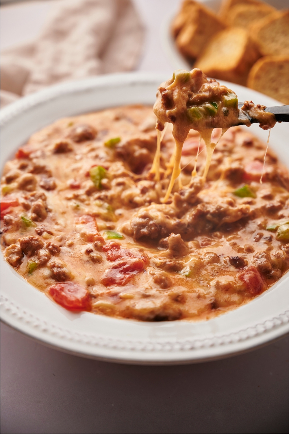 Rotel dip being scoop out of a bowl filled with the dip by a spoon.