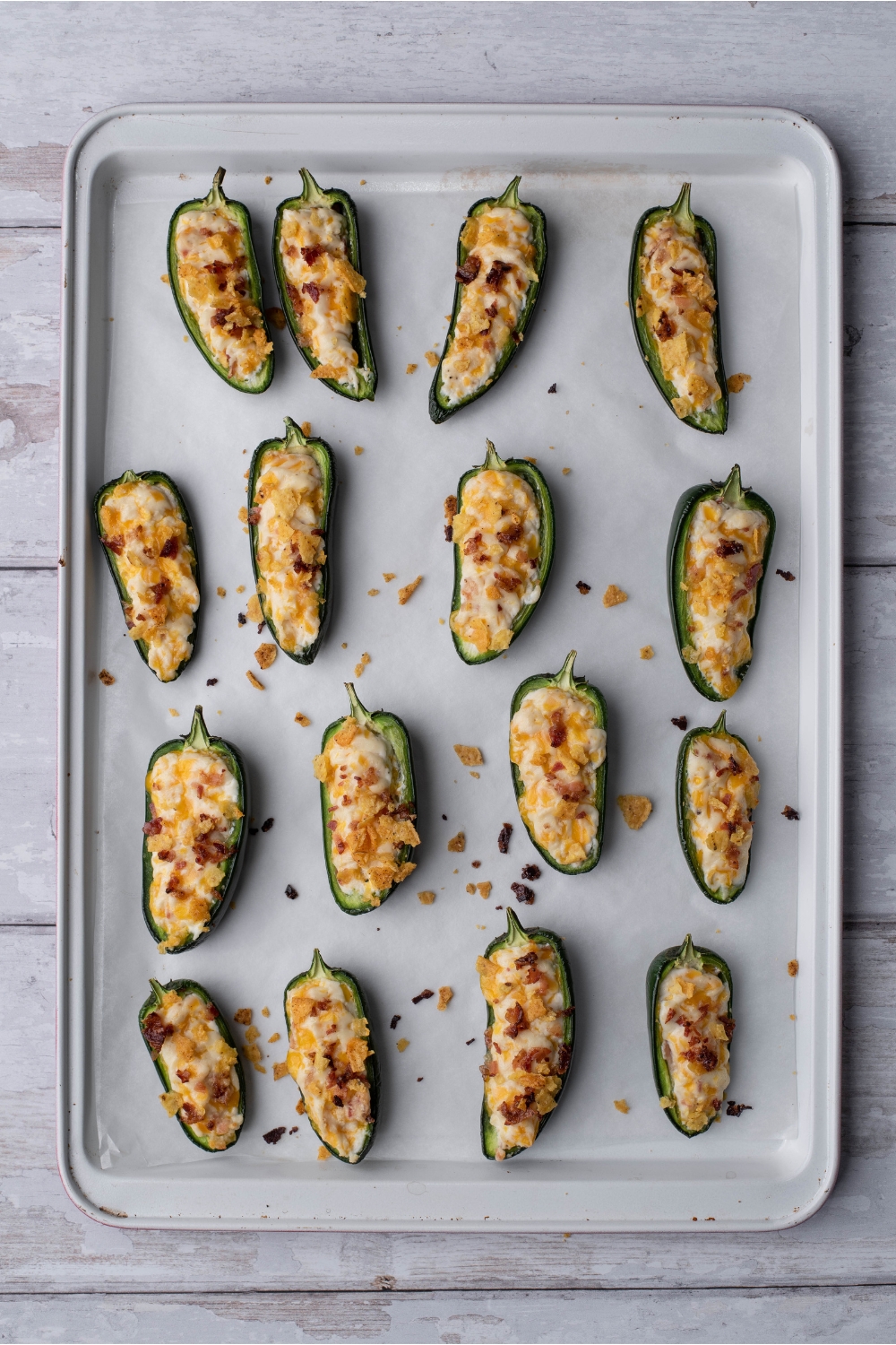 Freshly baked cream cheese stuffed jalapeño poppers lined on a baking sheet with parchment paper.
