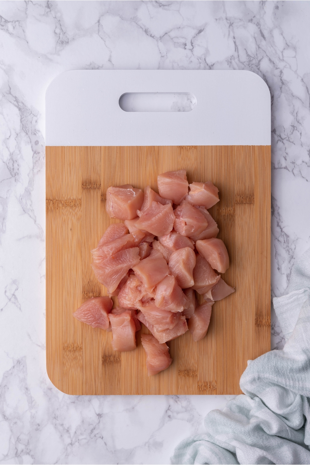 Raw chicken breast pieces on a wood cutting board.