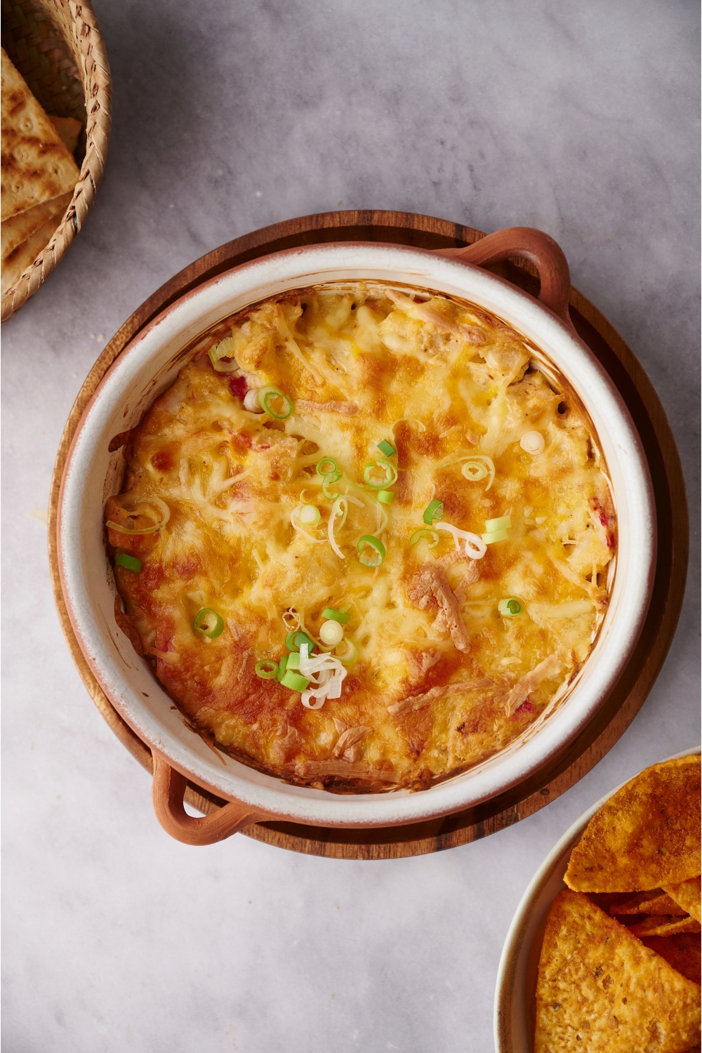Crab dip in a white and brown baking dish garnished with diced green onion.