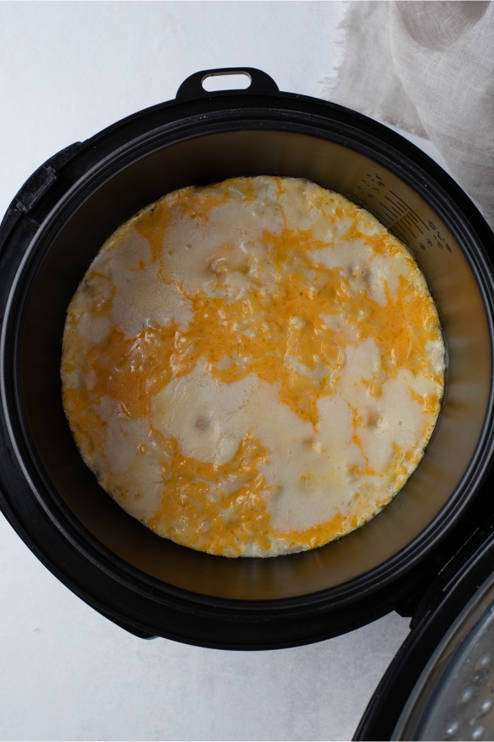 Crockpot filled with a mixture of creamy soup and melted cheese.