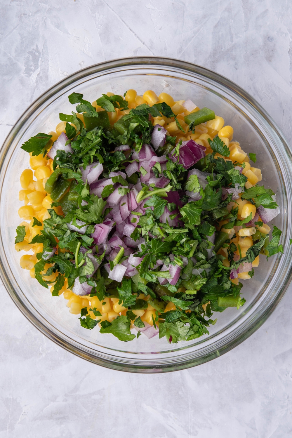A mixing bowl with the corn salsa ingredients added to it.
