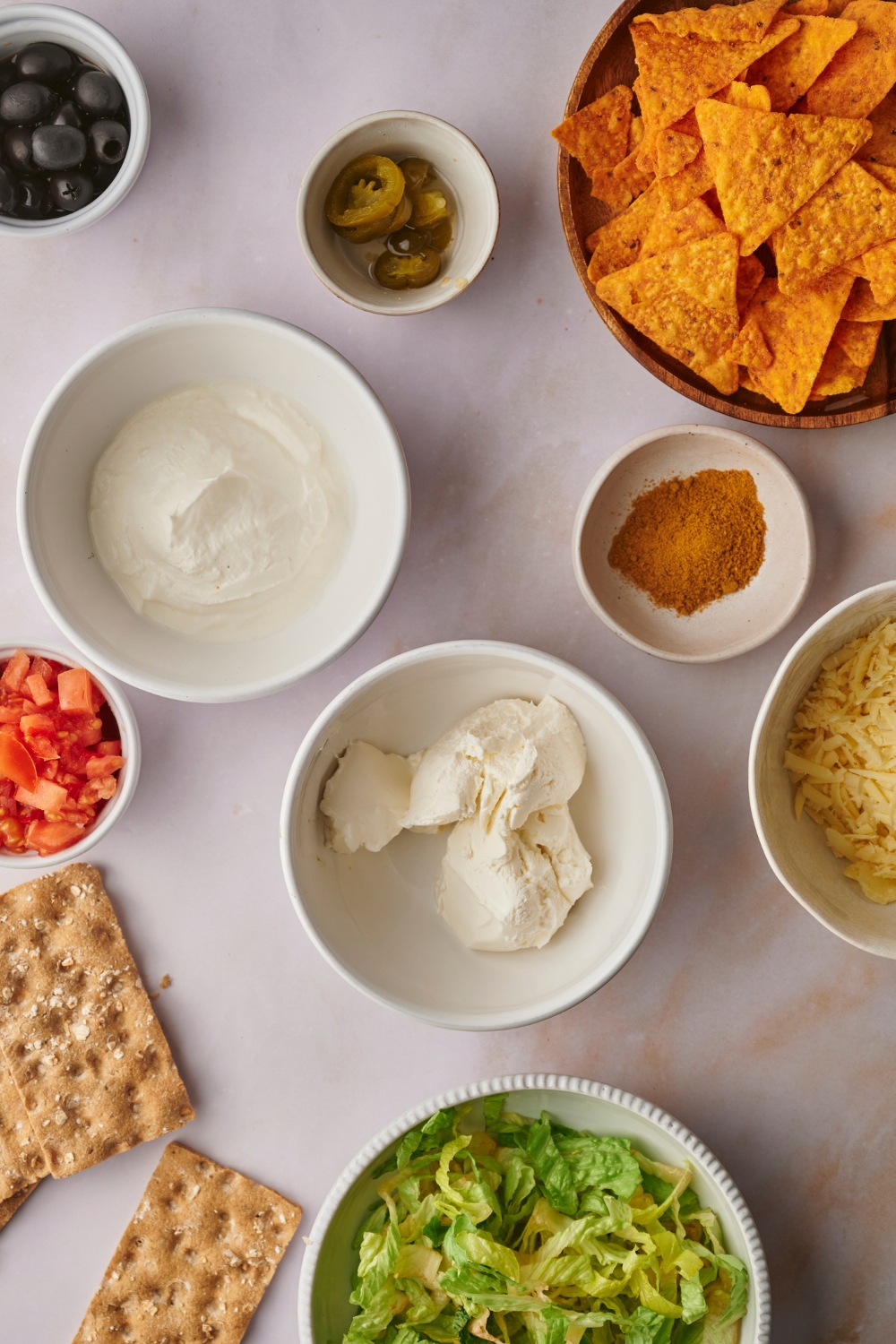 A countertop with multiple bowls with ingredients to make taco dip.