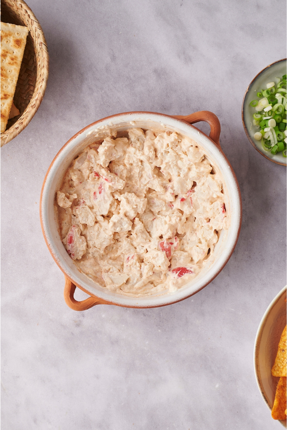 Overview of unbaked crab dip in a white and brown baking dish.