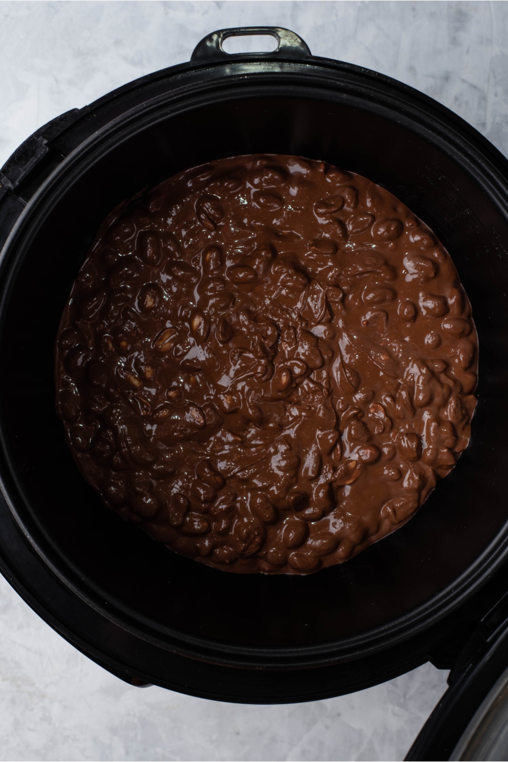 Crock pot filled with peanuts covered in melted chocolate.