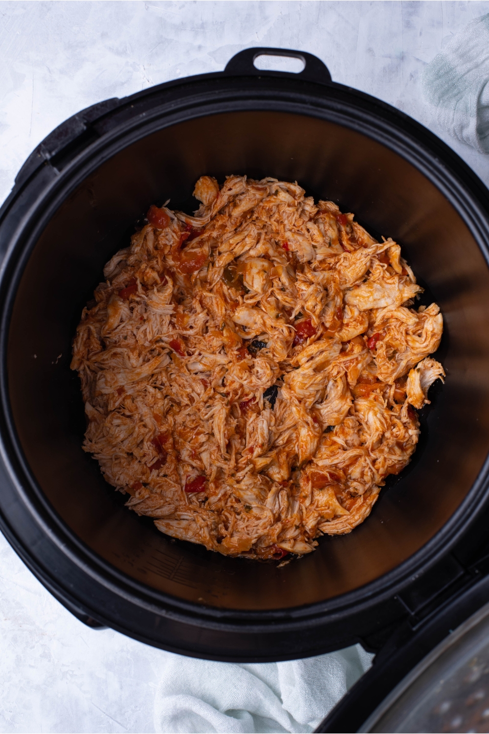 Slow cooker filled with cooked and shredded salsa chicken.