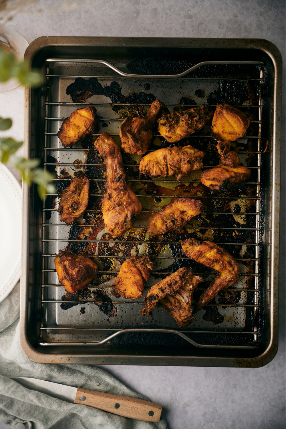Tandoori chicken on a grill pan on top of a roasting pan.