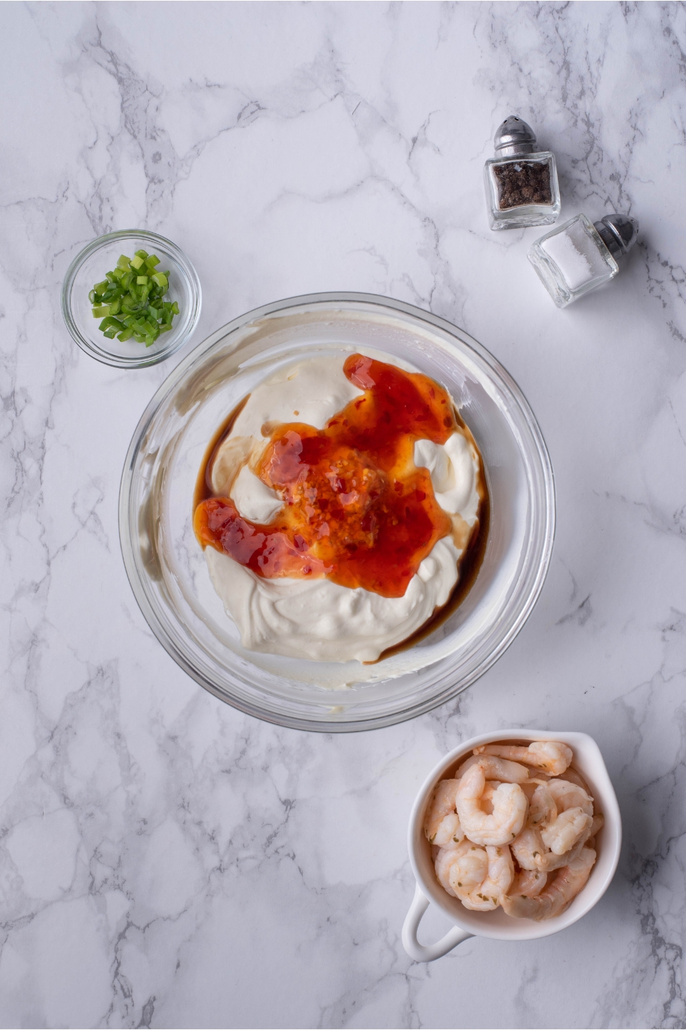 Clear bowl filled with cream cheese, red chili sauce, and Worcestershire sauce.