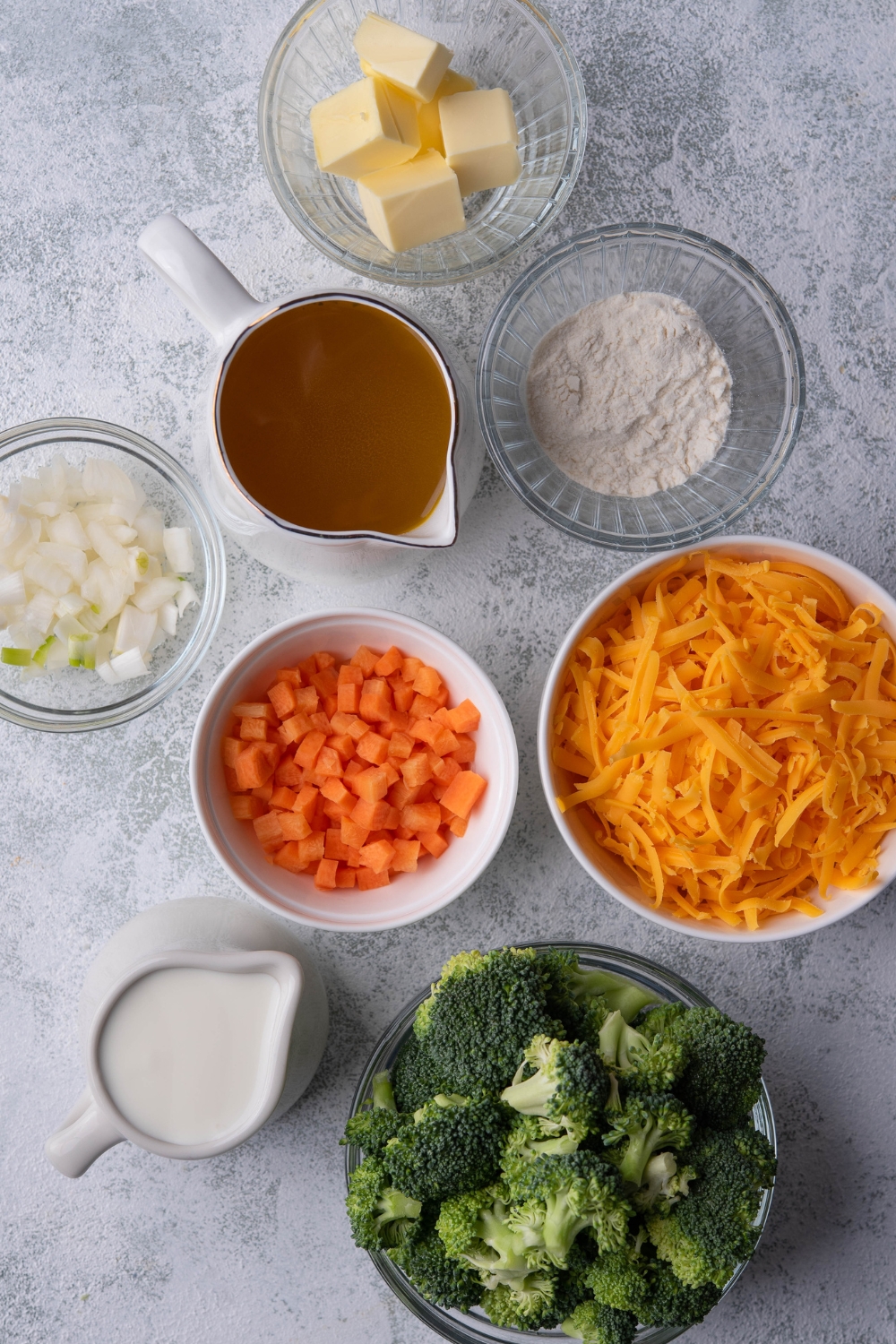 A countertop with the ingredients to make broccoli cheese soup.