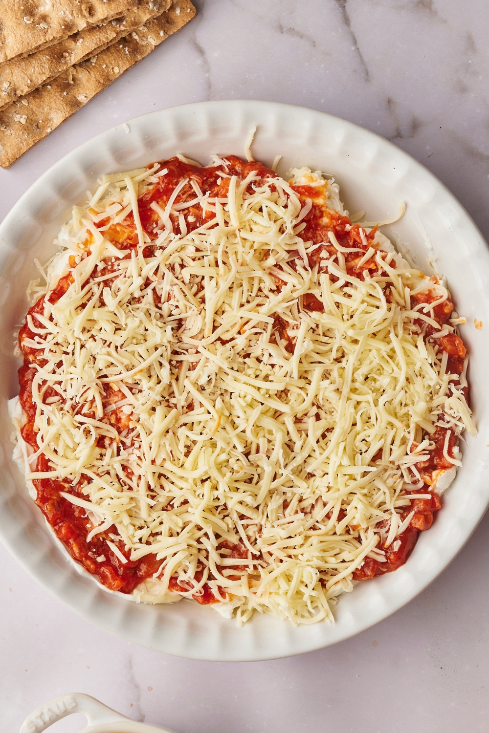 A pie dish with a layer of cheese, pizza sauce and another layer of cheese.
