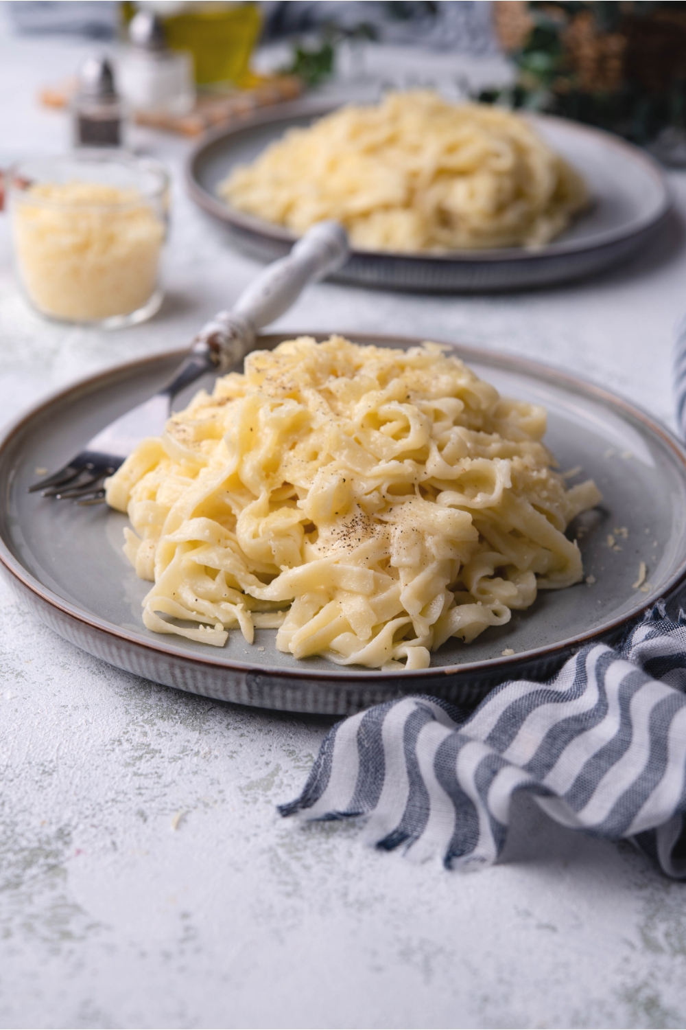 A serving of parmesan noodles on a plate with a fork on it.