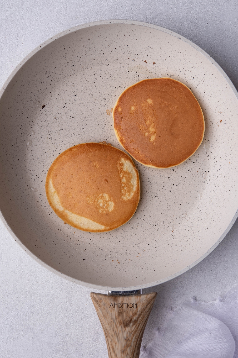 A skillet cooking two pancakes.