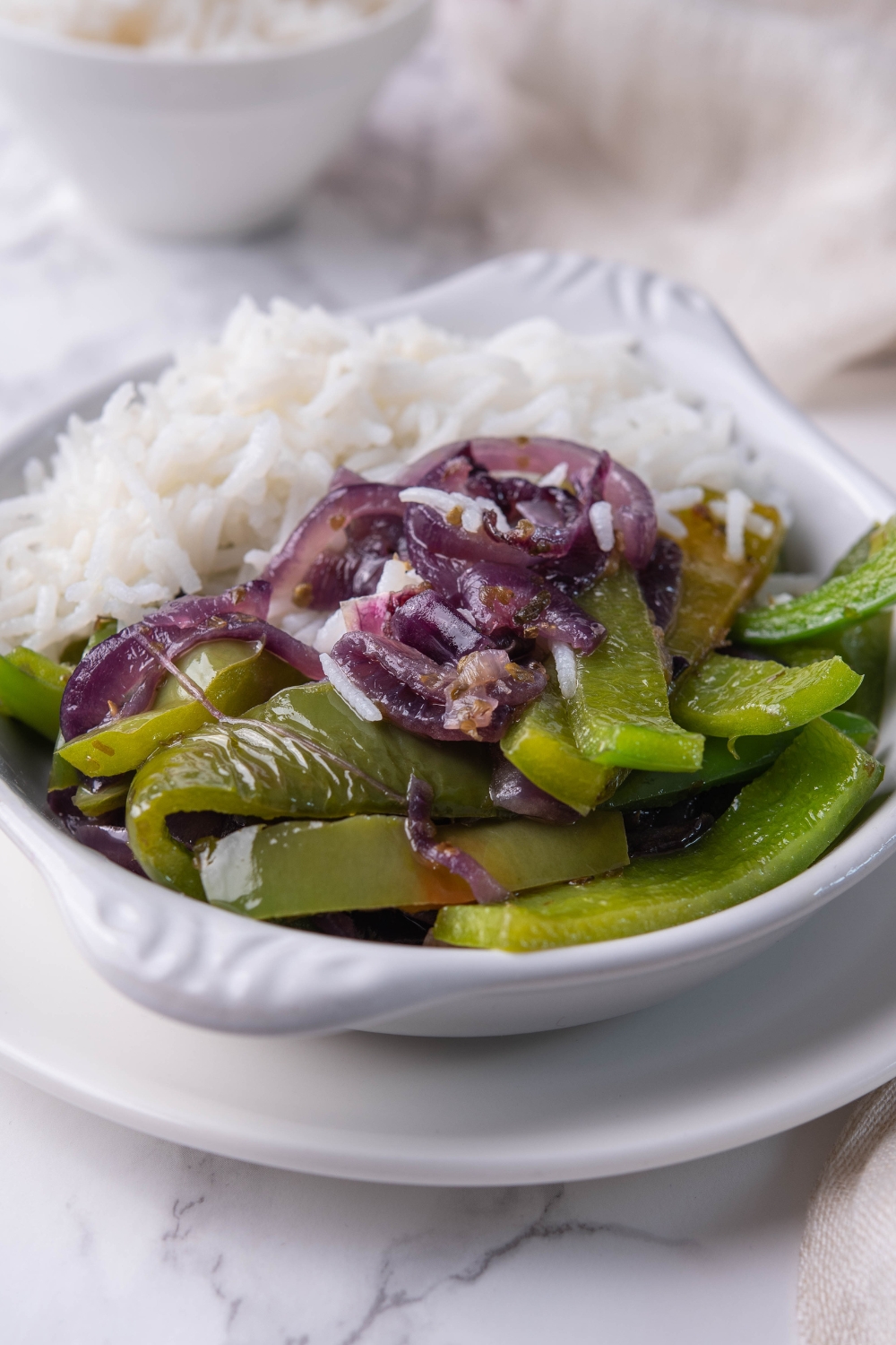 A serving dish with white rice and chipotle fajita veggies.