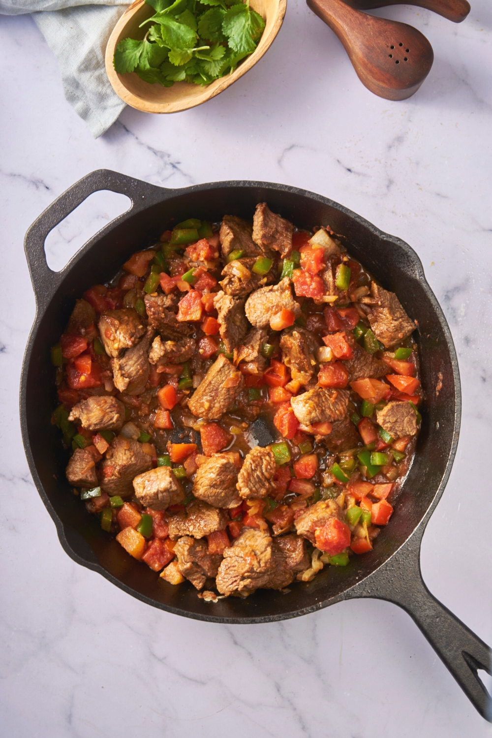 Stew meat chunks, tomatoes, green bell pepper, and onion in a pan.