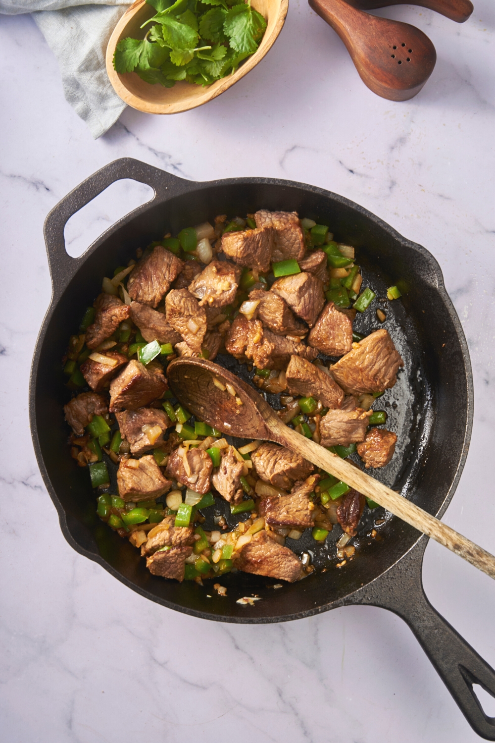 Stew meat, diced onion, and green pepper cooking in a pan.