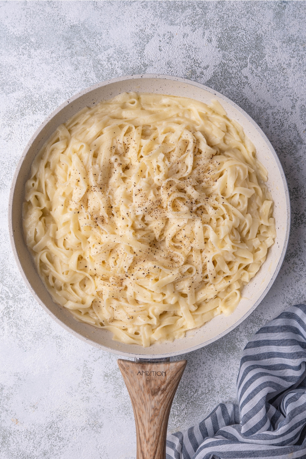 Pepper on top of buttered noodles in a skillet.