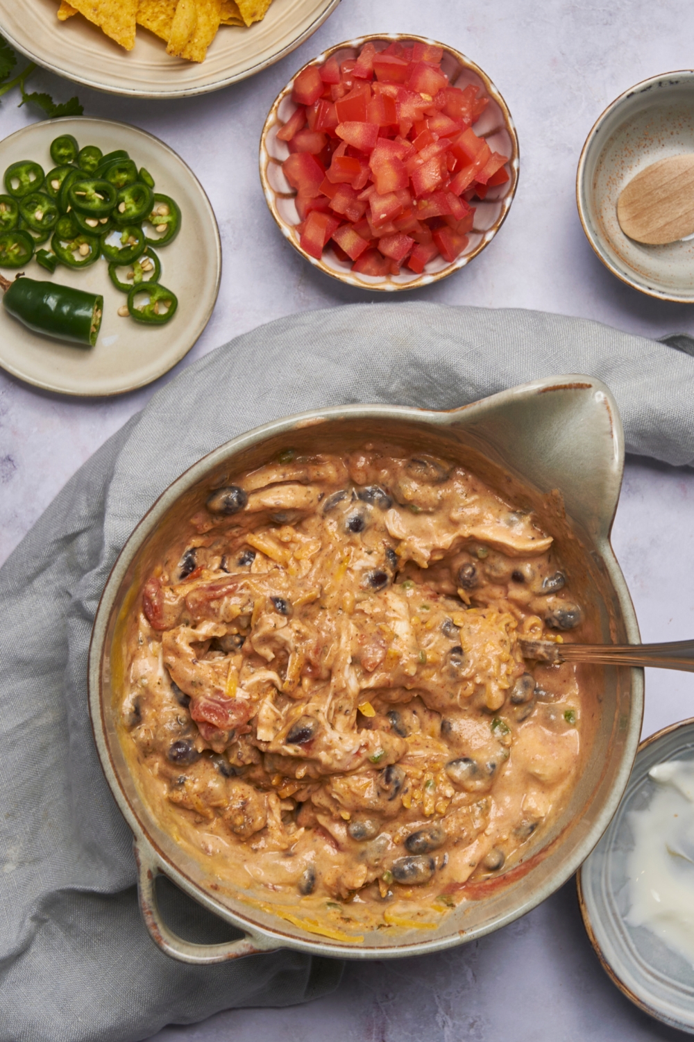 A creamy mixture that has shredded cheddar cheese, black beans, shredded chicken, and tomatoes in it.