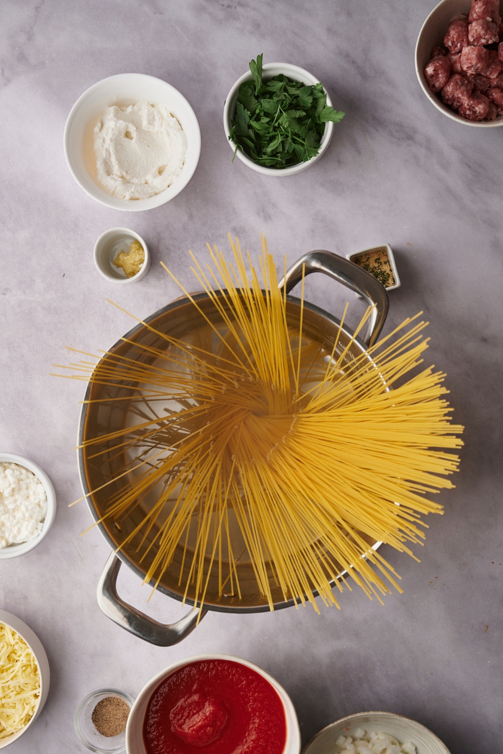 A countertop covered with multiple bowls with the ingredients needed to make million dollar spaghetti casserole.