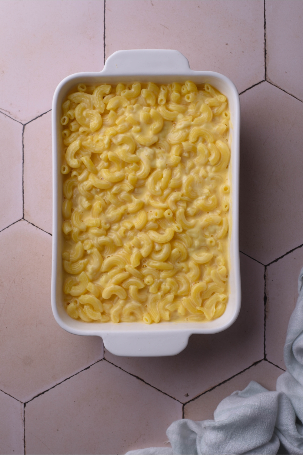 A white baking dish filled with elbow macaroni in a creamy cheese sauce.