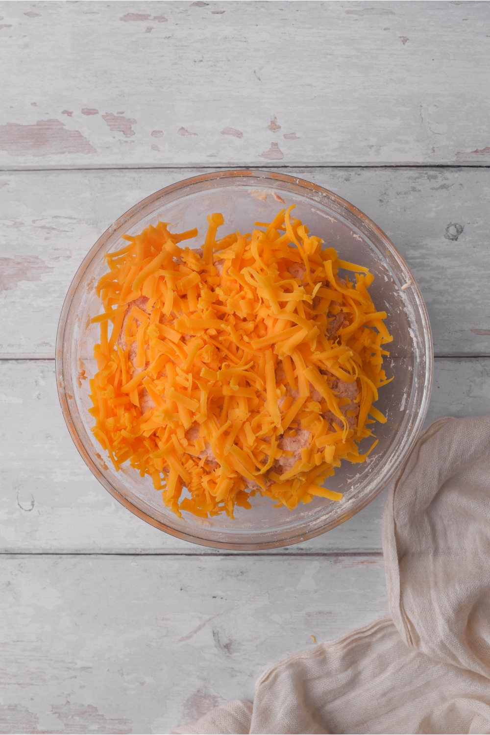 A clear bowl filled with shredded cheese.