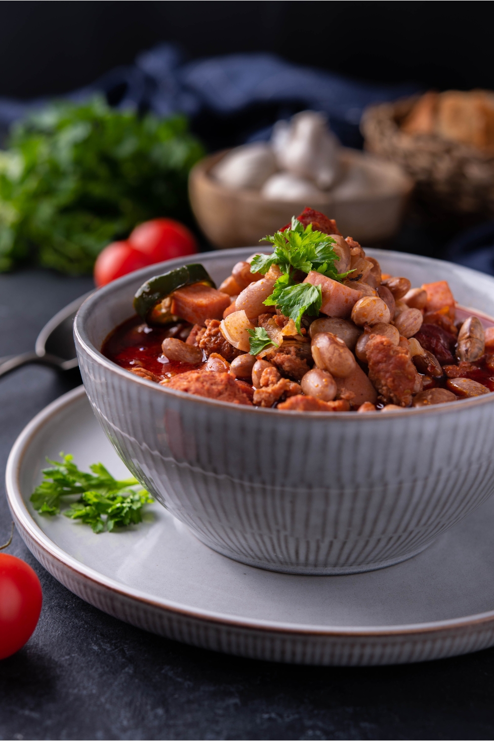 Charro beans in a blue bowl atop a blue plate, garnished with fresh herbs.