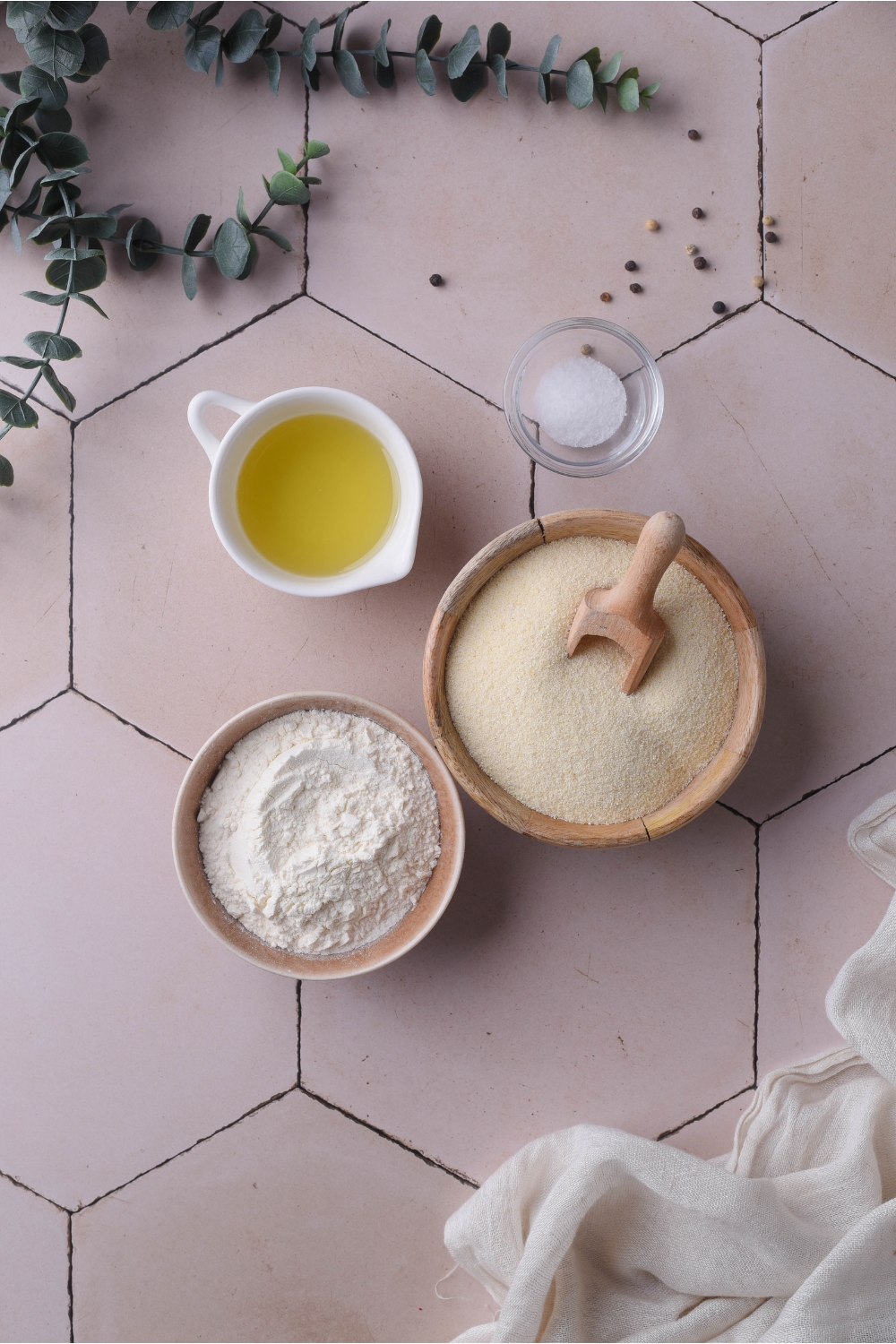 An assortment of ingredients including bowls of flour, grits, oil, and salt.