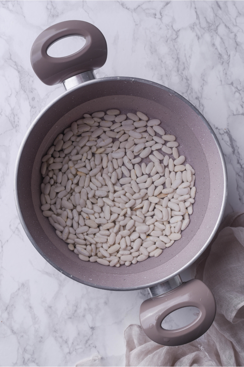 A grey pot filled with dried white beans.