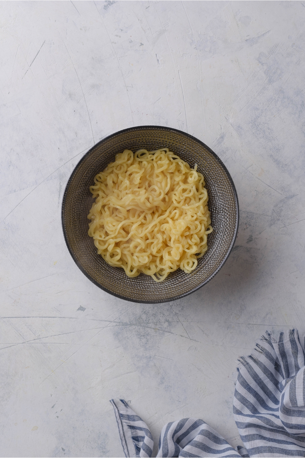 A black bowl filled with cooked ramen noodles.