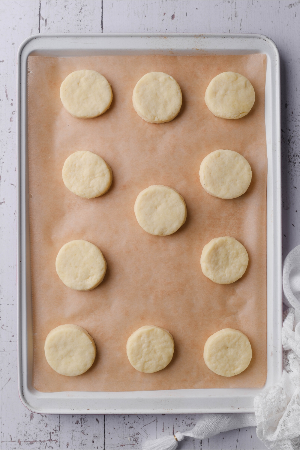 Circles of unbaked biscuit dough on a baking sheet lined with parchment paper.