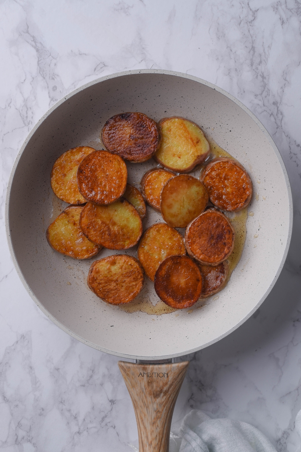 A frying pan with golden brown sliced potatoes.